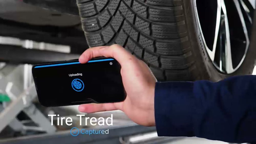 Anyline / TireBuddy, stage 4: Immediately after the sweep the phone shows a dark screen 'Uploading' with a spinning tire
